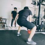 パーソナルジムでケトルベルを持ち、正しいフォームで筋持久力を高めるトレーニングを行う様子。