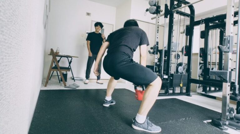 パーソナルジムでケトルベルを持ち、正しいフォームで筋持久力を高めるトレーニングを行う様子。