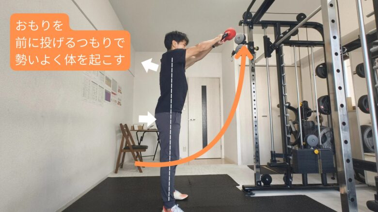金山のただたんパーソナルジムのトレーナーが、ケトルベルスイングの動き(おもりを前に振り上げながら勢いよく立ち上がる)を解説している様子。