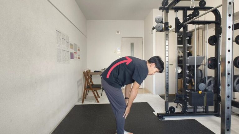 金山のパーソナルジムのトレーナーが、トレーニングで特に注意が必要な腰を丸めたフォームの見本を示す様子。初心者への丁寧なフォーム指導。