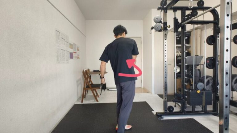 金山のパーソナルジムのトレーナーが、体幹をひねる動きの実演を通して、柔軟性の向上やウォーミングアップの方法を指導している様子。