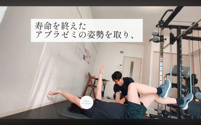 金山のパーソナルジム「ただたん」にて、トレーナーがクライアントに「デッドバグ」の動作を指導している様子。仰向けで手足を動かし、体幹の「静」と手足の「動」を使い分けるトレーニング。